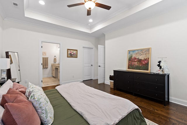 bedroom featuring a tray ceiling, ceiling fan, crown molding, connected bathroom, and dark hardwood / wood-style floors