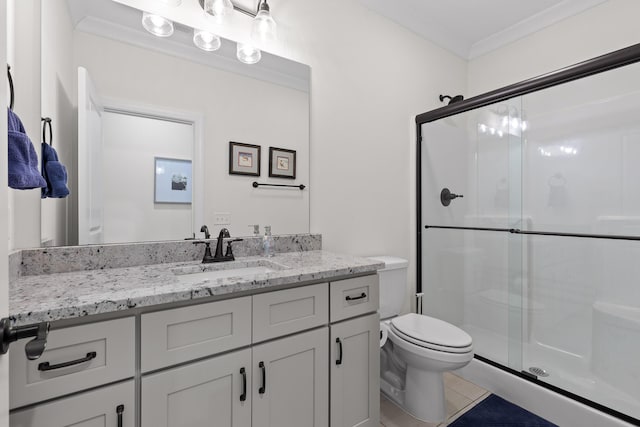 bathroom with vanity, toilet, a shower with door, and ornamental molding