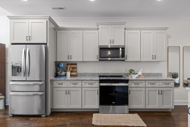 kitchen with stainless steel appliances, light stone counters, and dark wood-type flooring