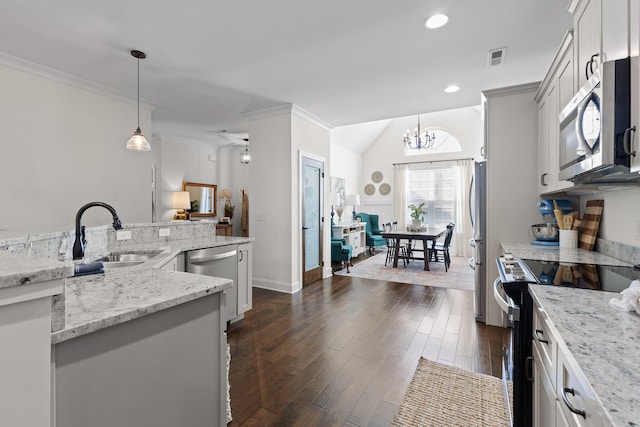 kitchen with light stone countertops, dark hardwood / wood-style flooring, stainless steel appliances, sink, and hanging light fixtures