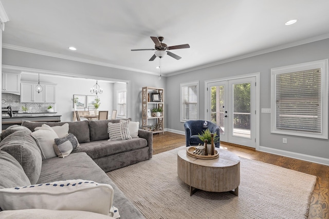 living room with ceiling fan with notable chandelier, wood-type flooring, ornamental molding, and french doors