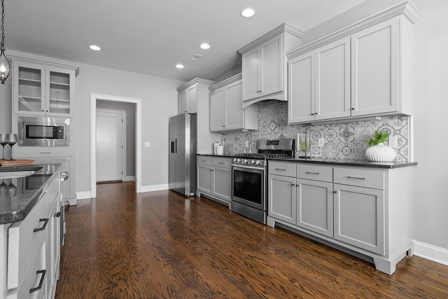 kitchen featuring pendant lighting, dark stone counters, dark hardwood / wood-style floors, tasteful backsplash, and stainless steel appliances