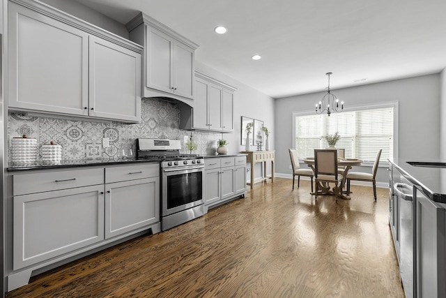 kitchen with dark wood-type flooring, tasteful backsplash, a notable chandelier, pendant lighting, and stainless steel stove