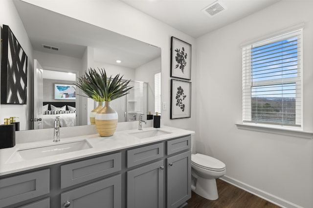 bathroom with hardwood / wood-style floors, vanity, toilet, and a shower with shower door