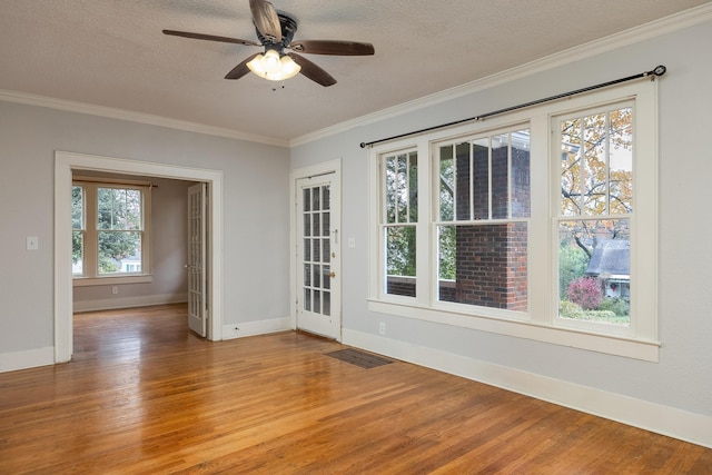 spare room with a textured ceiling, hardwood / wood-style flooring, and a healthy amount of sunlight