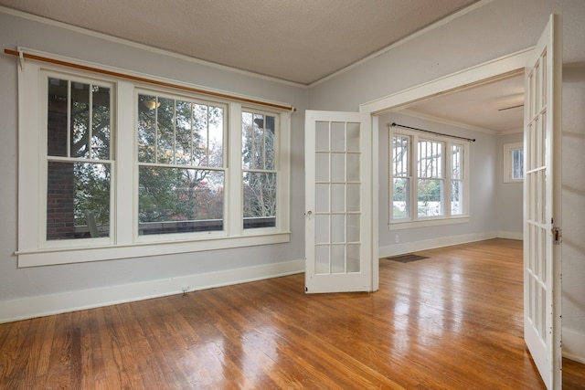 spare room with crown molding, french doors, a textured ceiling, and hardwood / wood-style flooring