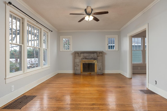 unfurnished living room with plenty of natural light, ceiling fan, a stone fireplace, and light hardwood / wood-style flooring