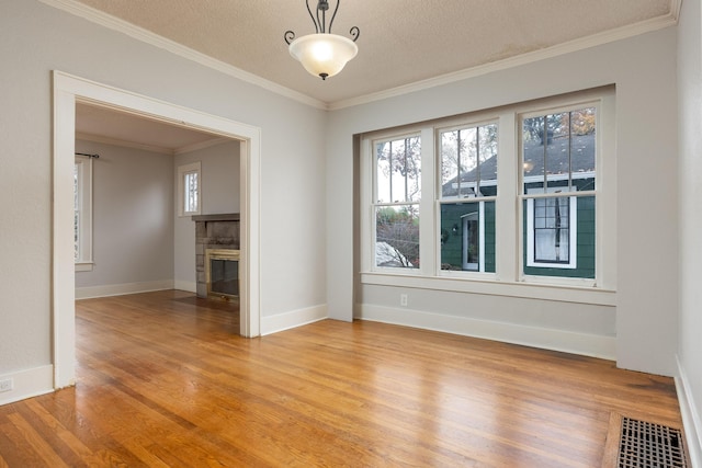 spare room featuring a fireplace, crown molding, hardwood / wood-style floors, and a textured ceiling