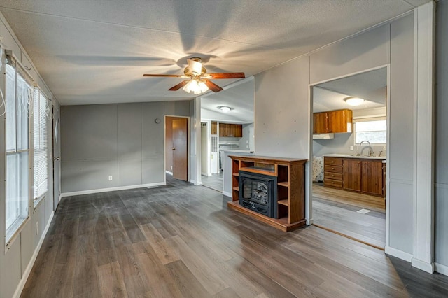 unfurnished living room with ceiling fan, a healthy amount of sunlight, wood-type flooring, and vaulted ceiling