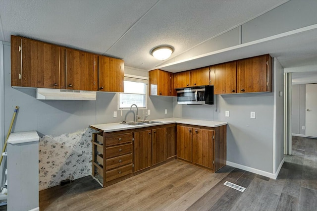 kitchen featuring a textured ceiling, wood-type flooring, and sink