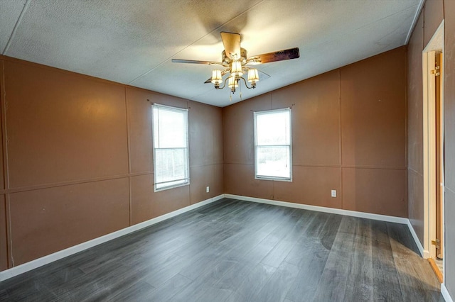 empty room with ceiling fan, dark hardwood / wood-style floors, and vaulted ceiling