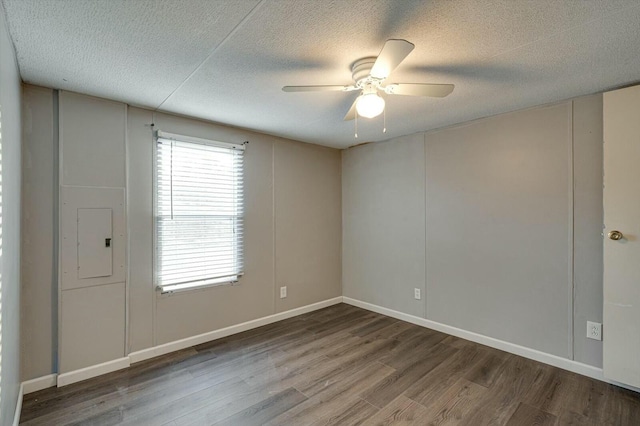 empty room with ceiling fan, a healthy amount of sunlight, wood-type flooring, and electric panel