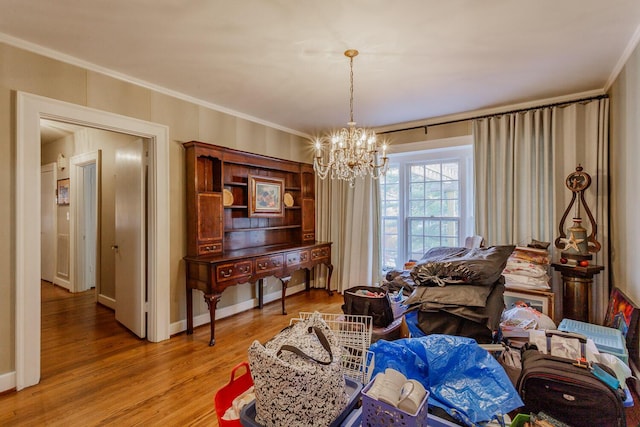 sitting room featuring hardwood / wood-style floors, ornamental molding, and a notable chandelier