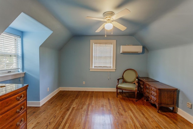 sitting room featuring vaulted ceiling, light hardwood / wood-style flooring, a wall mounted AC, and ceiling fan