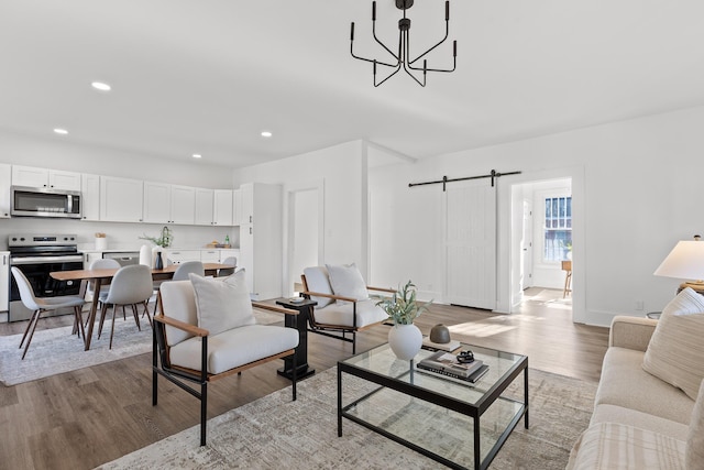 living room with a barn door, hardwood / wood-style floors, and a notable chandelier