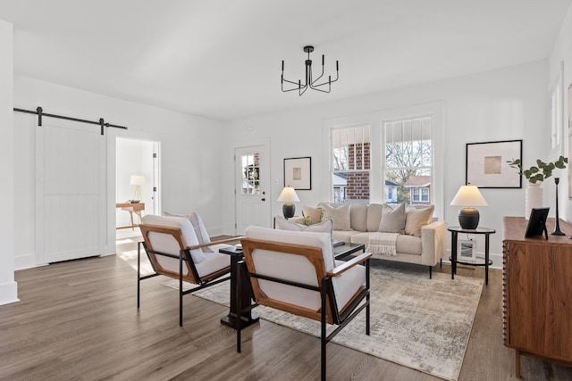 living room with a barn door, an inviting chandelier, and dark wood-type flooring