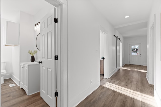 hall with wood-type flooring and a barn door