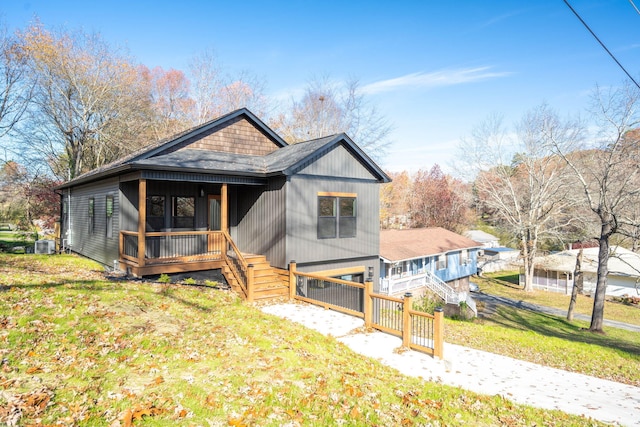 bungalow-style house with a front yard, covered porch, and central air condition unit