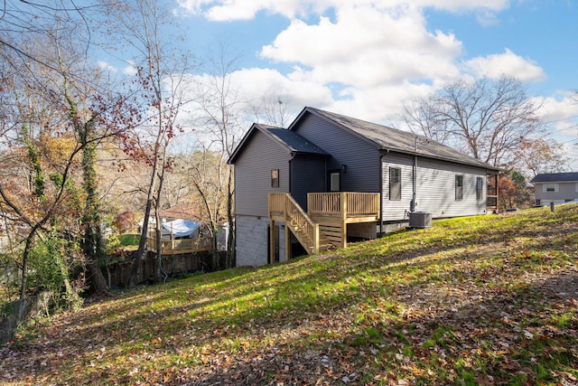 exterior space with a yard, a wooden deck, and central air condition unit