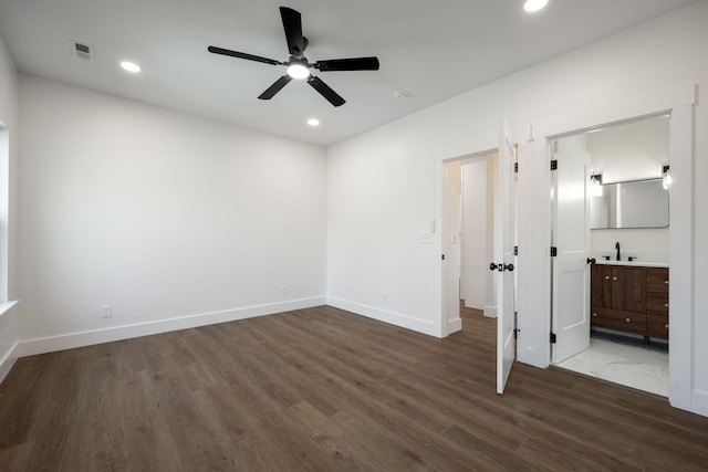 unfurnished bedroom featuring ensuite bathroom, sink, ceiling fan, and dark wood-type flooring