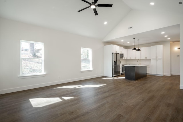 unfurnished living room with ceiling fan, sink, high vaulted ceiling, and dark wood-type flooring