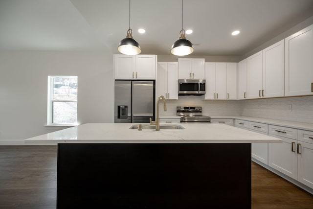 kitchen with light stone counters, sink, an island with sink, and stainless steel appliances