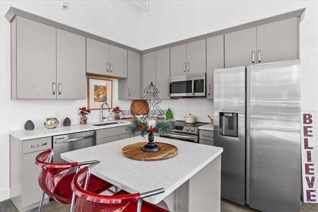 kitchen featuring sink, a center island, stainless steel appliances, a breakfast bar area, and gray cabinets