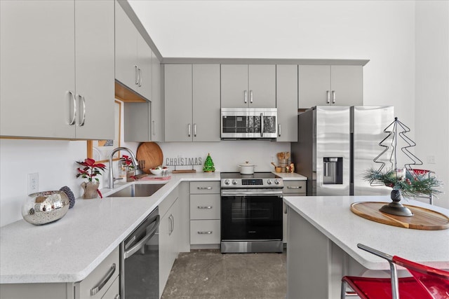 kitchen with gray cabinetry, a kitchen breakfast bar, sink, and stainless steel appliances