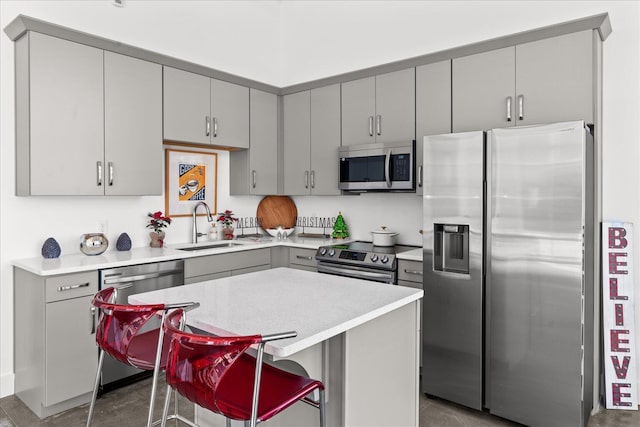 kitchen featuring sink, stainless steel appliances, a kitchen bar, gray cabinets, and a kitchen island