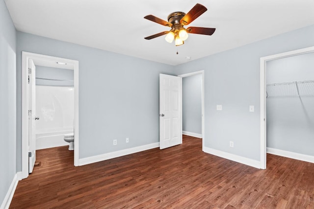 unfurnished bedroom with a walk in closet, ensuite bathroom, ceiling fan, and dark hardwood / wood-style floors