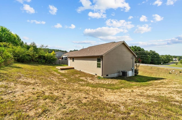 view of side of property featuring a lawn and central AC