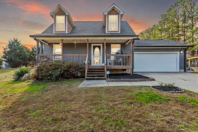 cape cod-style house with a porch, a yard, and a garage