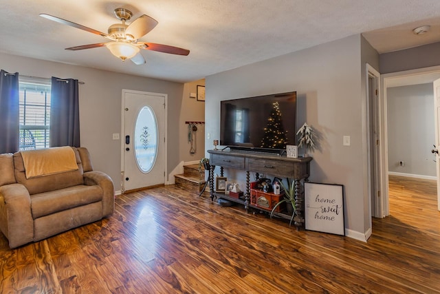 living room with dark wood-type flooring, a textured ceiling, and ceiling fan