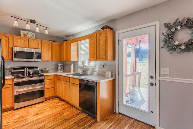 kitchen with stainless steel appliances, sink, and light hardwood / wood-style flooring