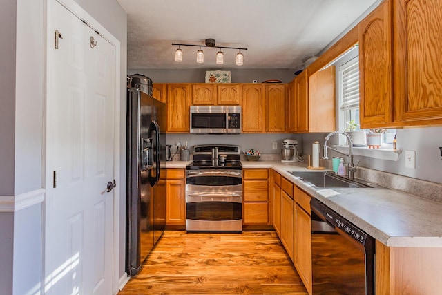 kitchen featuring sink, light hardwood / wood-style floors, and black appliances