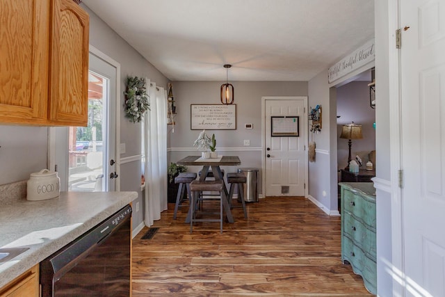 kitchen featuring dark wood-type flooring, decorative light fixtures, and black dishwasher