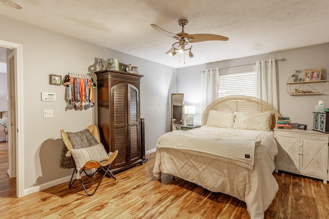 bedroom with ceiling fan, a textured ceiling, and light wood-type flooring