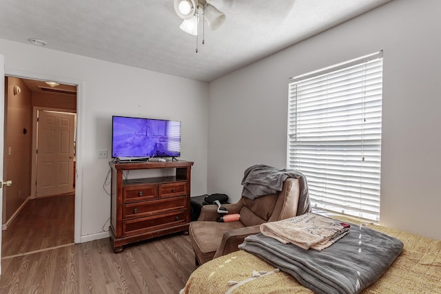 bedroom with ceiling fan, wood-type flooring, and a textured ceiling