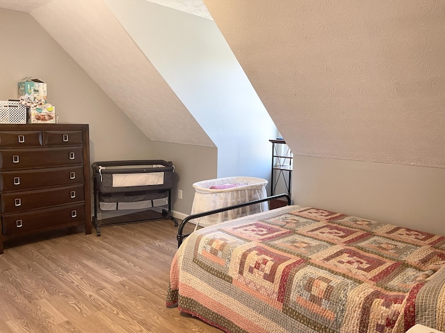 bedroom featuring lofted ceiling, a textured ceiling, and light wood-type flooring