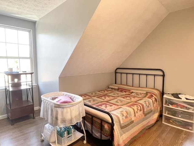 bedroom featuring wood-type flooring, vaulted ceiling, and a textured ceiling