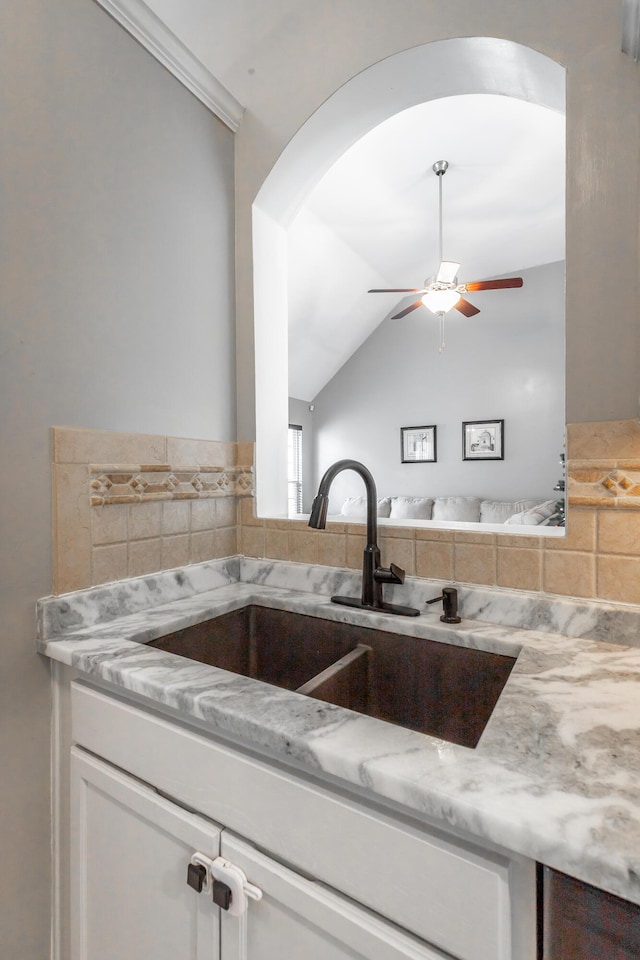 kitchen featuring light stone countertops, ceiling fan, lofted ceiling, and sink