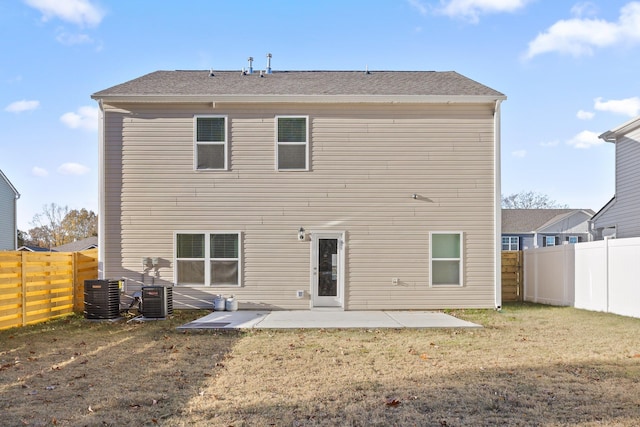 back of property with central AC, a patio area, and a lawn