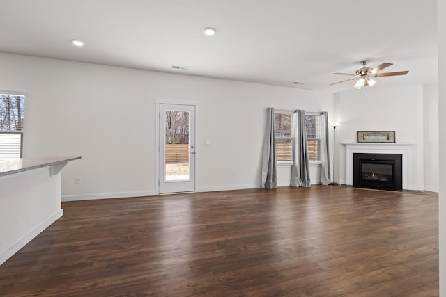 unfurnished living room featuring dark hardwood / wood-style floors, ceiling fan, and a wealth of natural light