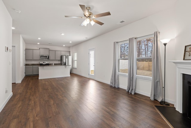 unfurnished living room with ceiling fan and dark wood-type flooring