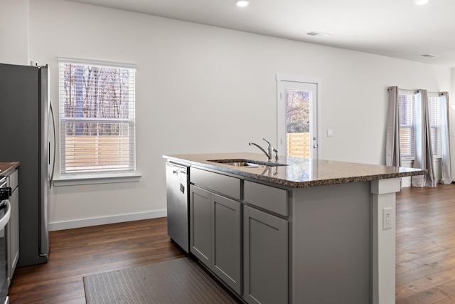 kitchen with appliances with stainless steel finishes, a kitchen island with sink, a healthy amount of sunlight, and sink