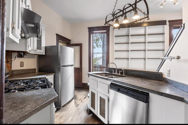 kitchen featuring sink, decorative light fixtures, white cabinetry, wood-type flooring, and stainless steel appliances