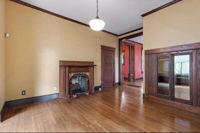 unfurnished living room featuring hardwood / wood-style flooring, crown molding, and french doors