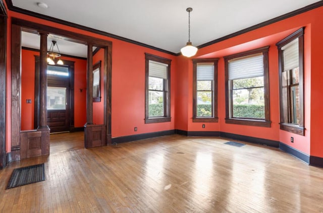 unfurnished room featuring wood-type flooring, ornamental molding, and decorative columns