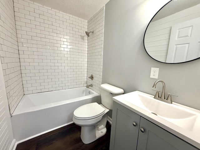 full bathroom with tiled shower / bath combo, wood-type flooring, a textured ceiling, toilet, and vanity