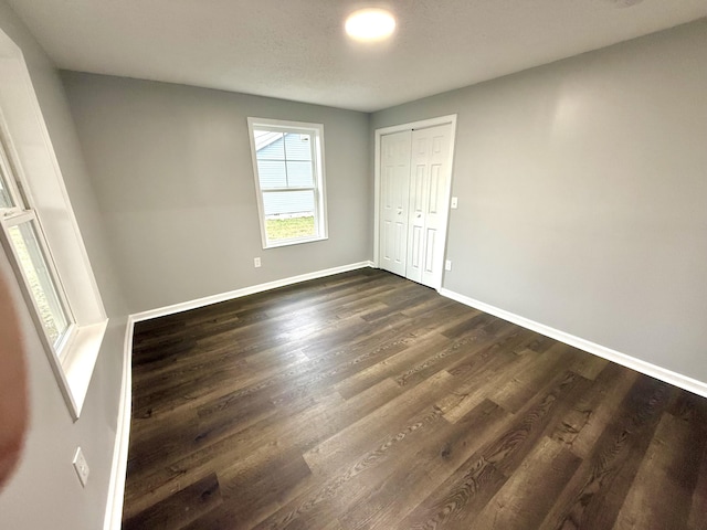 unfurnished bedroom with dark hardwood / wood-style flooring and a closet